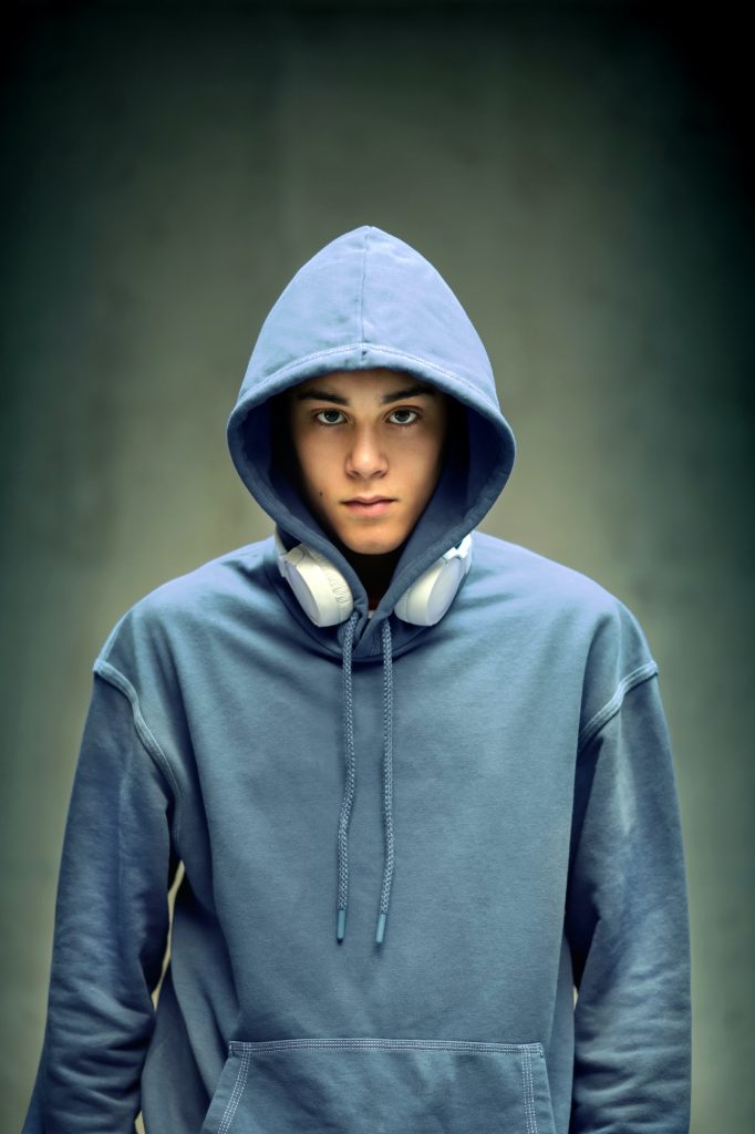 Moody serious teenage boy wearing a light blue hoodie
